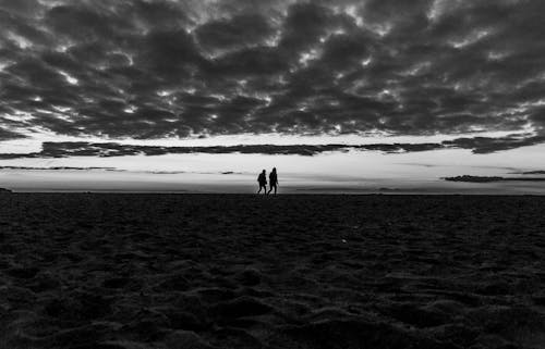 Two people stand on the beach at sunset