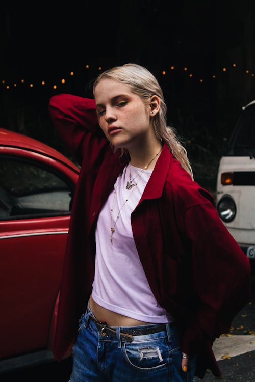женщина в пиджаке Re стоит возле красного автомобиля
