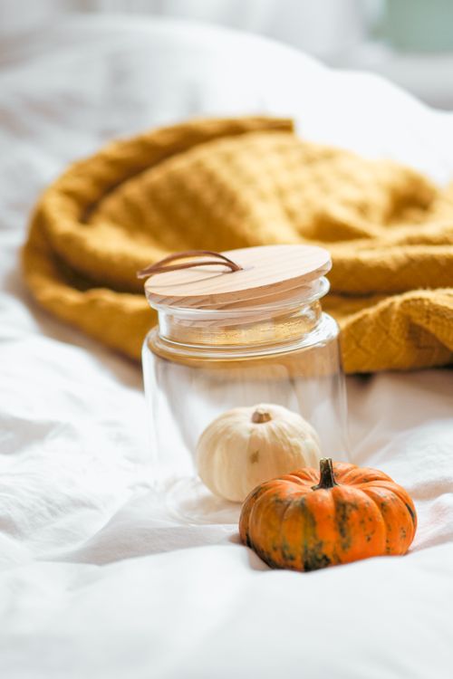 Free Glass jar and pumpkins on a white background with a cozy blanket, creating a warm autumn vibe. Stock Photo