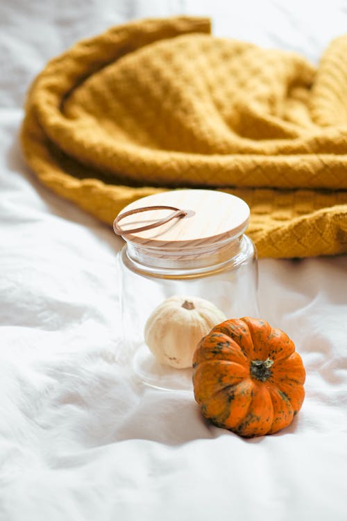 A jar of pumpkin and a blanket on a bed