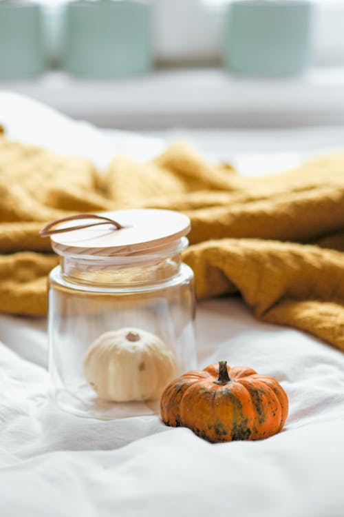 A jar with a pumpkin on top of a bed