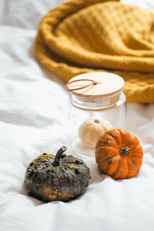 Pumpkins and a jar of honey on a bed