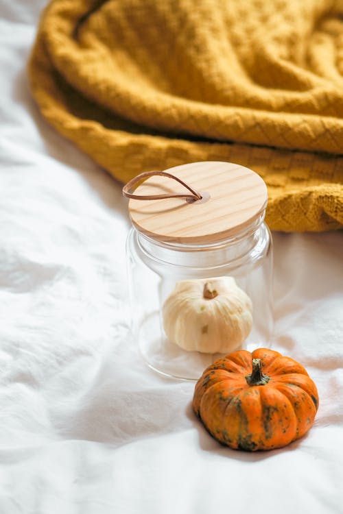 A jar with a pumpkin and a blanket on a bed