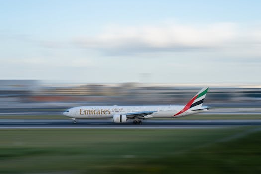 Emirates airplane speeding on runway with motion blur effect, illustrating travel excitement.