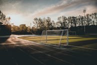 日落时分，空荡荡的足球场景色优美，球门柱与戏剧性的天空相映成趣