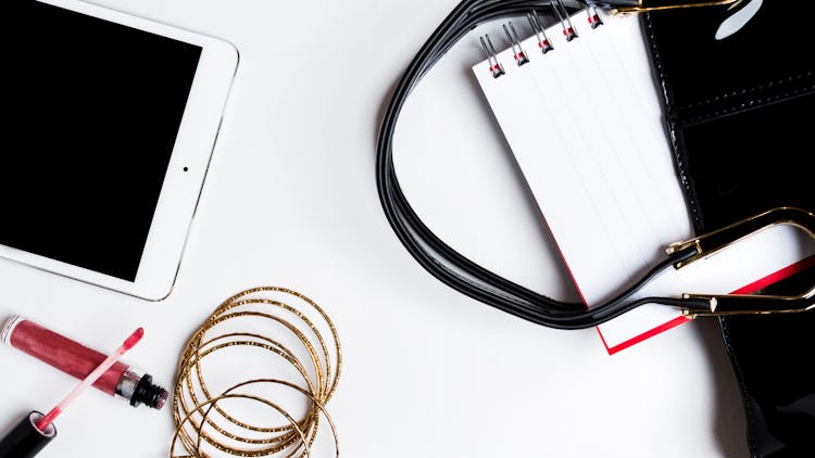 White Ipad Near Red Lip Gloss And Gold Bangles