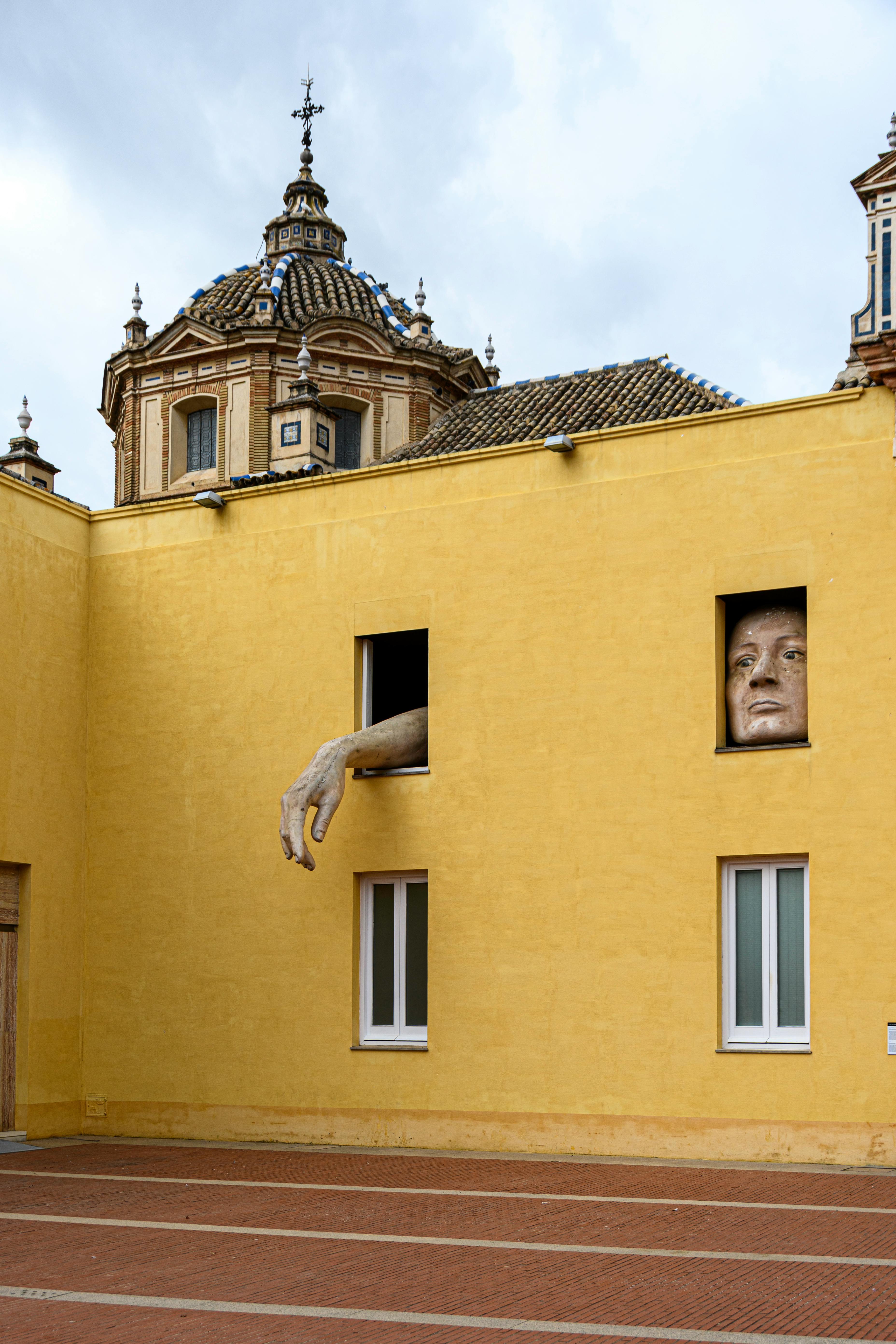 sculpture of hand and face in windows of building