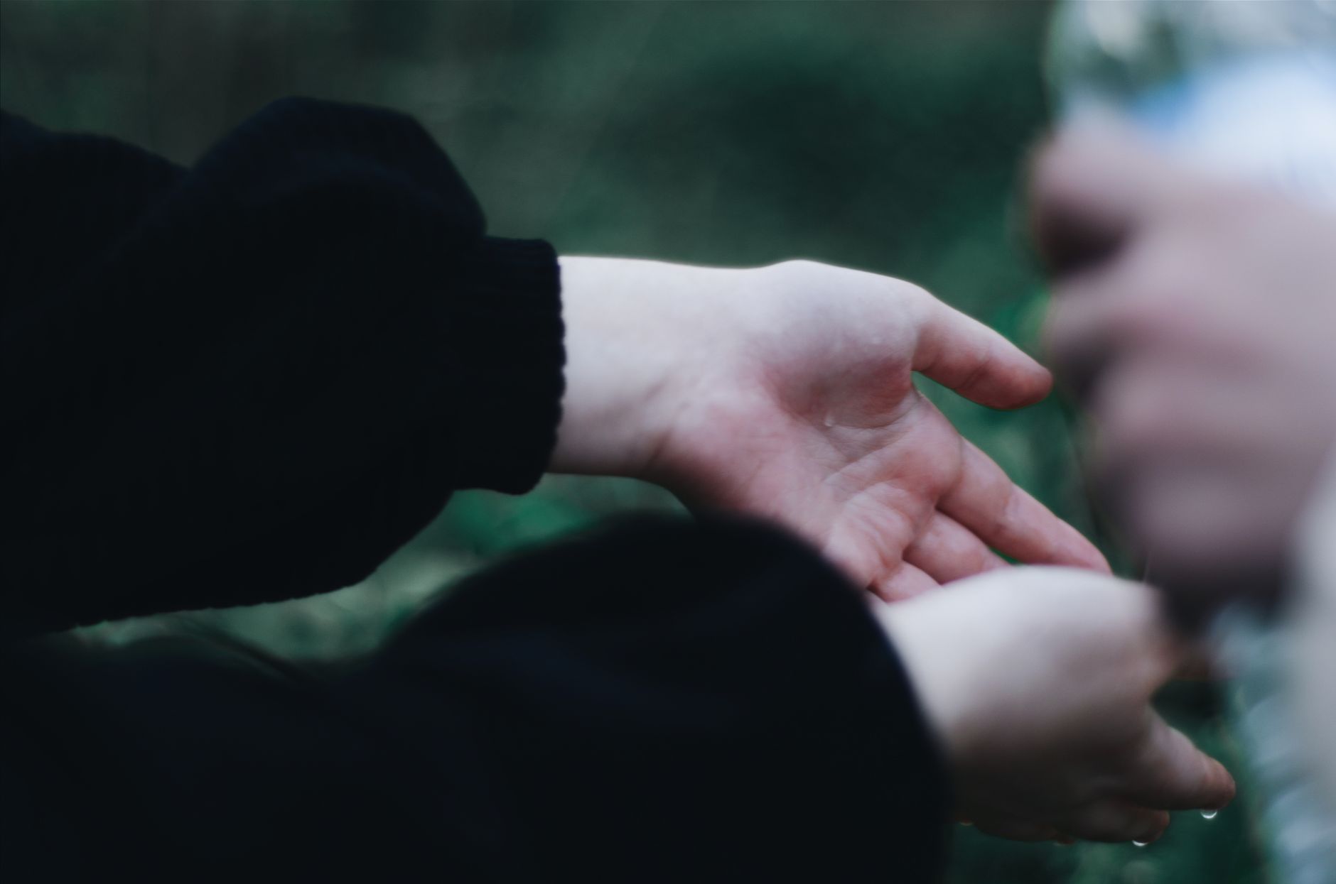 Detailed view of wet hands being washed outdoors, showcasing hygiene and care.