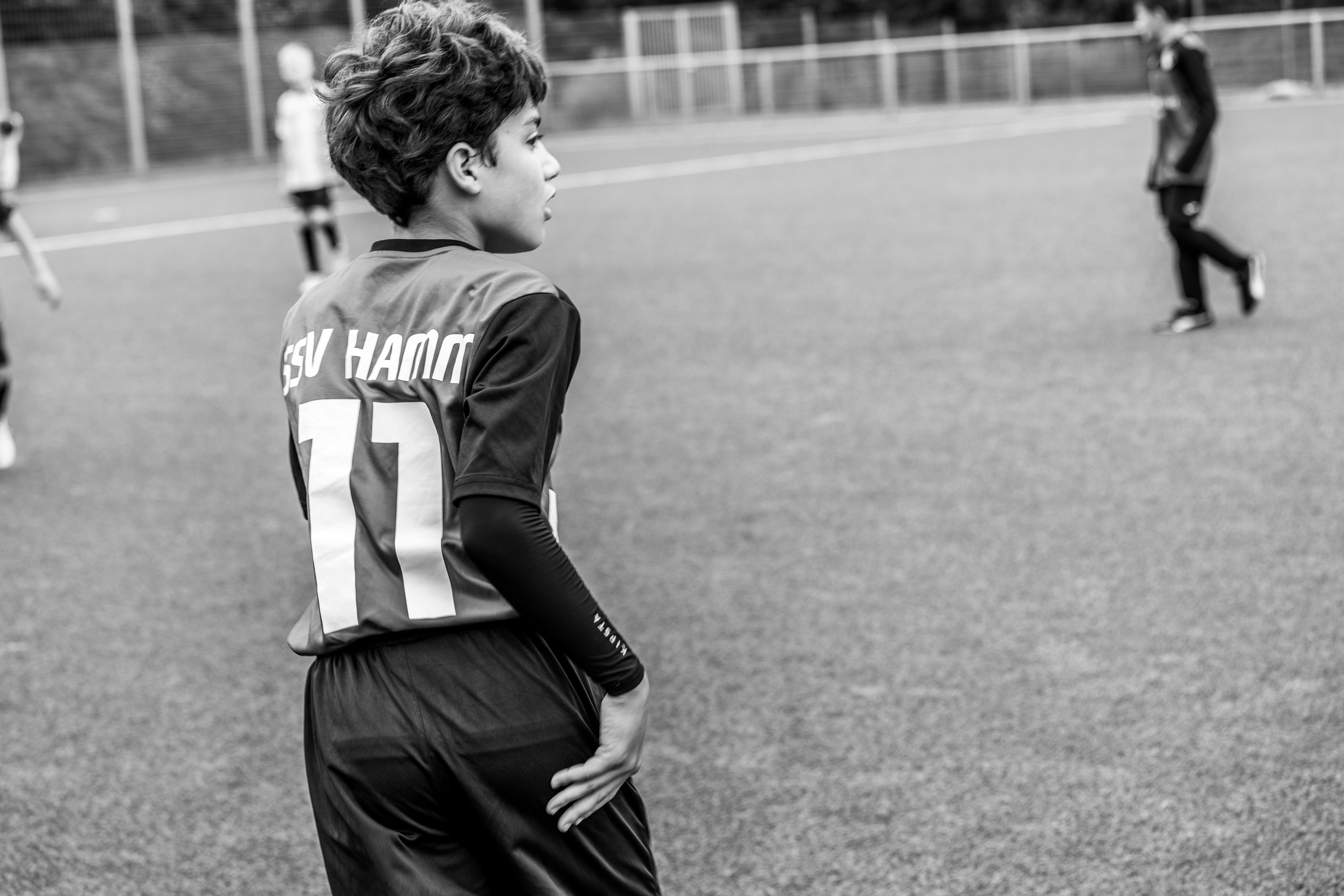 A young soccer player on a football pitch wearing a team jersey in Germany.