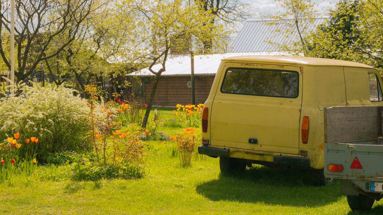 A van parked in a field with a truck in the background