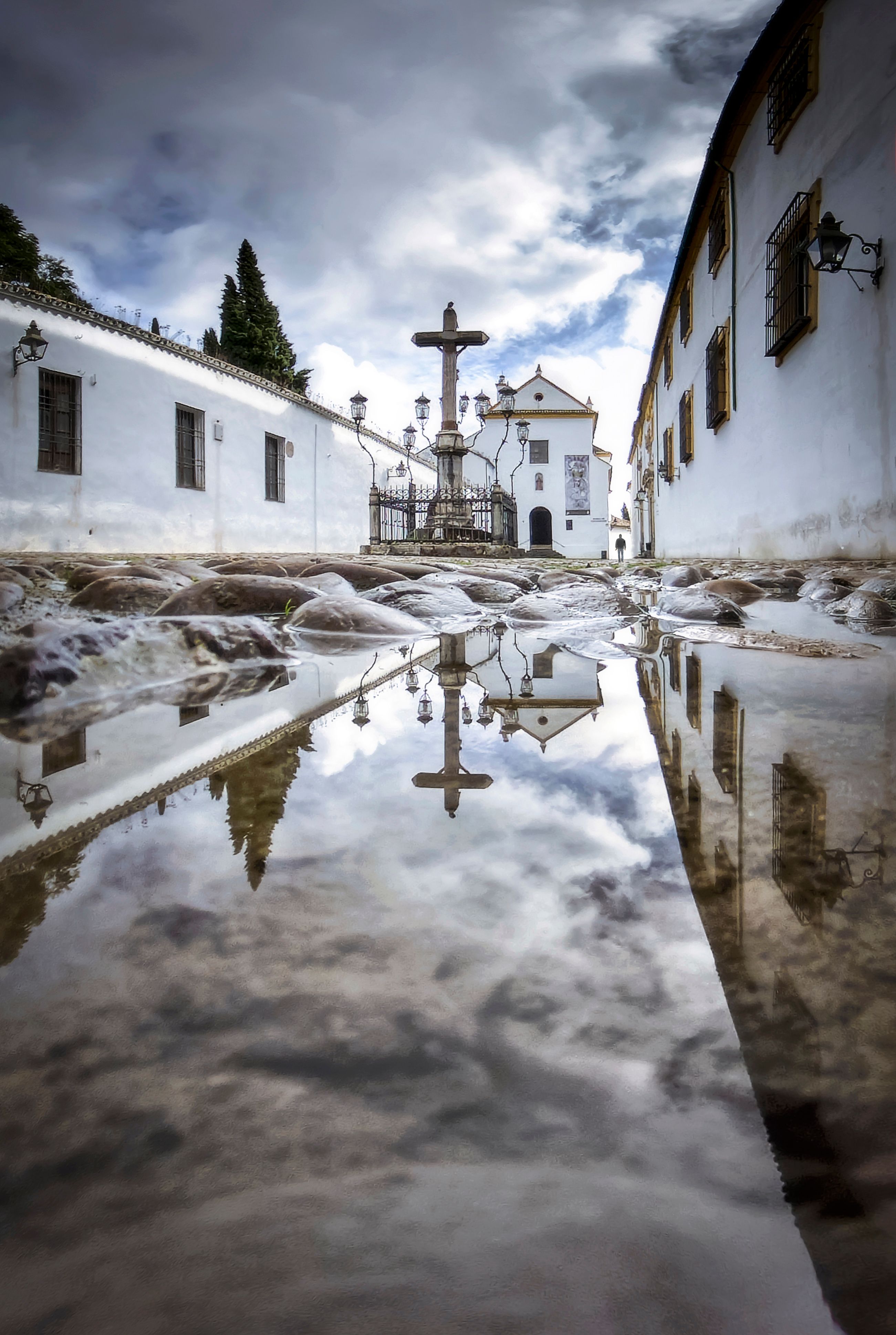 Dramatic view of the Christ of the Lanterns statue reflected in a puddle, Córdoba, Spain.