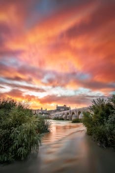 Stunning sunset view of Roman bridge and Guadalquivir River in Córdoba, Spain.