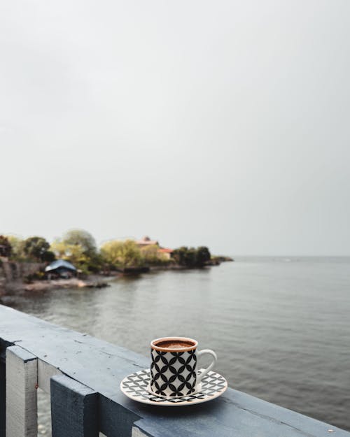 A cup of coffee on a table overlooking the water