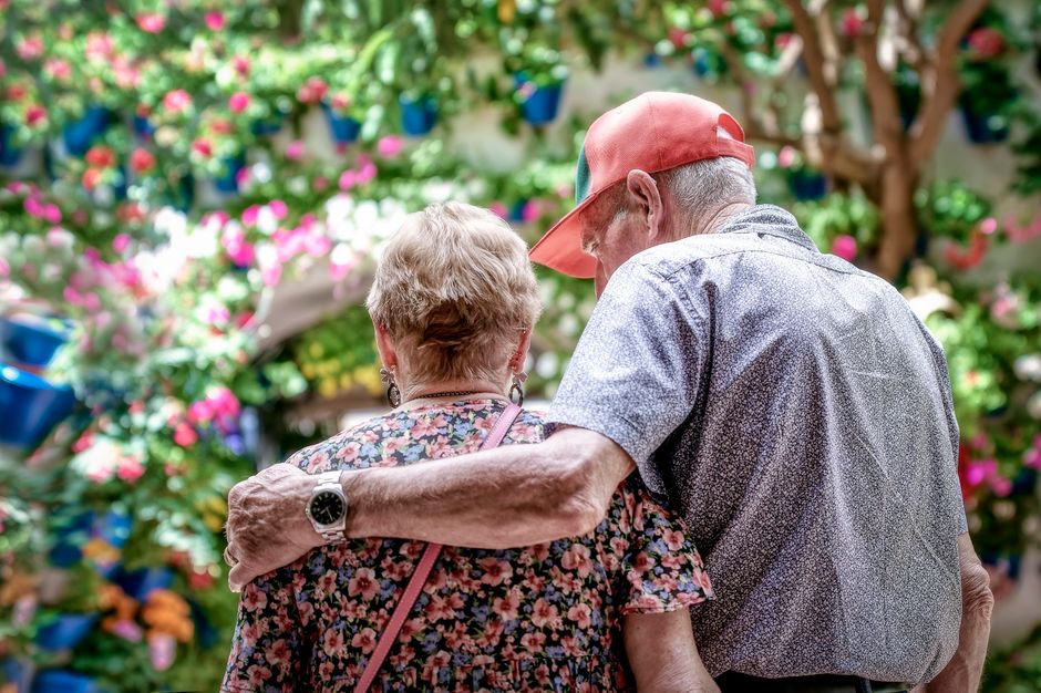 Una pareja mayor amorosa se abraza al aire libre en un jardín colorido en Córdoba, España.