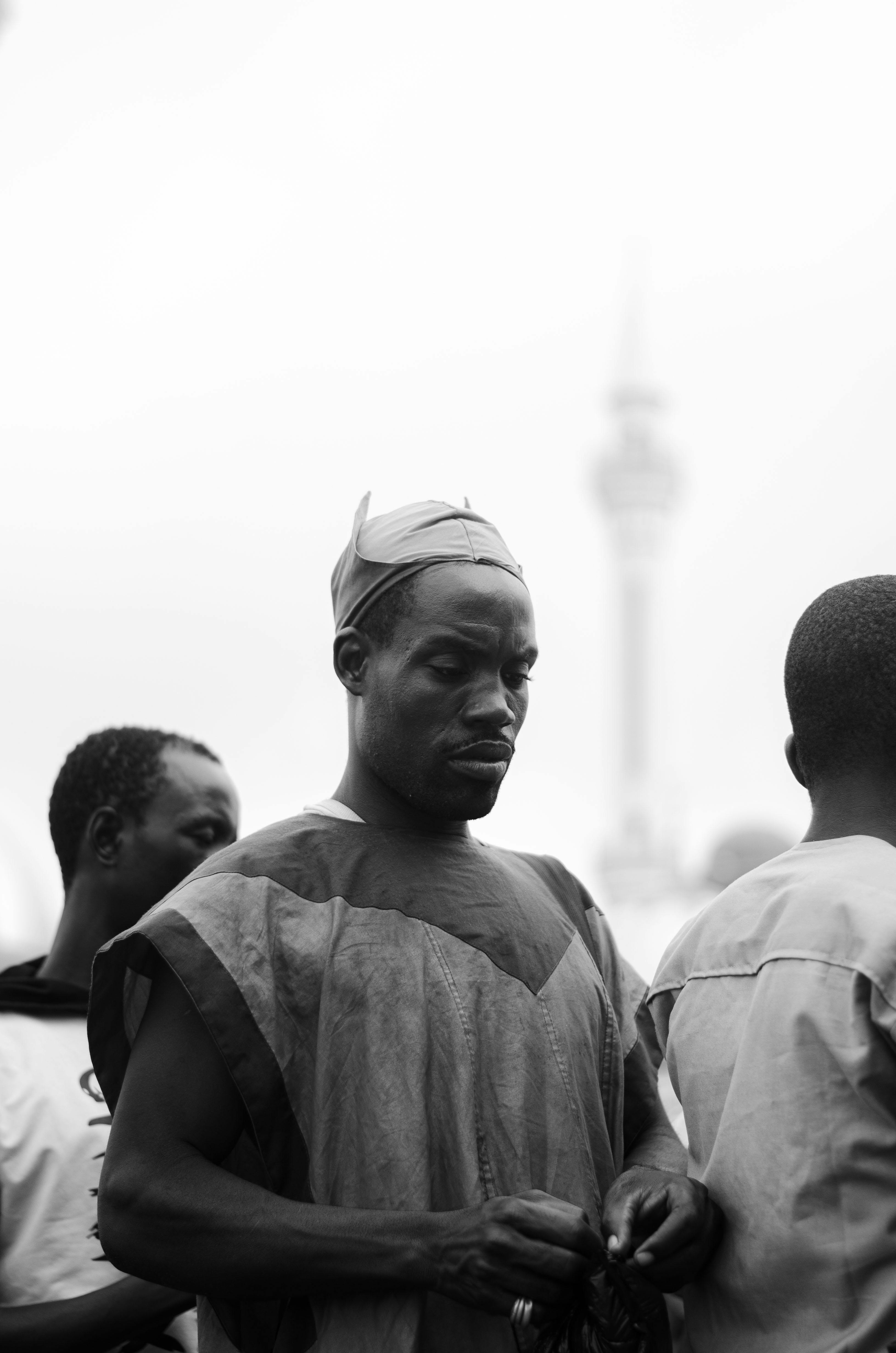 A thoughtful black and white portrait of African men in traditional attire outdoors against an urban background.
