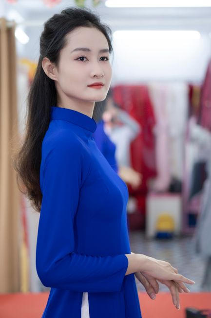 Graceful side profile of woman wearing vibrant blue ao dai, exuding elegance.