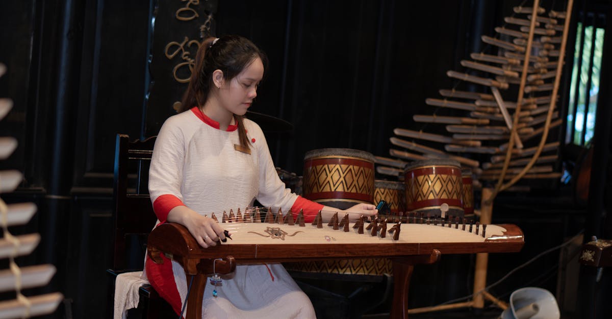 Woman in traditional attire skillfully playing the dan tranh instrument indoors.