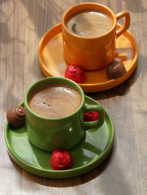 Two cups of coffee on saucers with chocolate and nuts