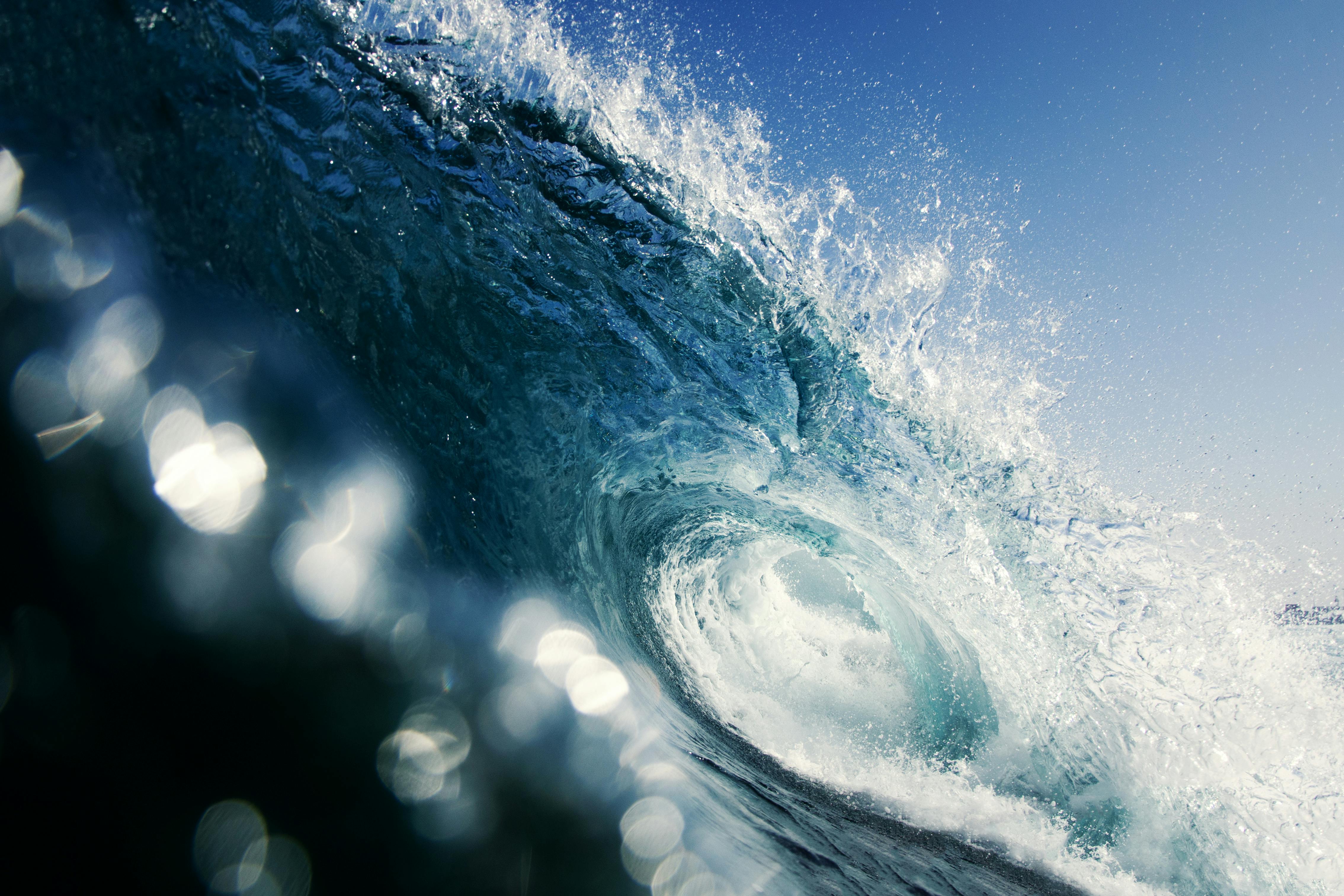 Dramatic close-up of a crashing ocean wave in Iquique, Chile, under a clear blue sky.