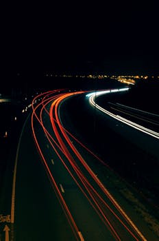 Long exposure photo capturing light trails on a highway at night, illustrating dynamic motion.