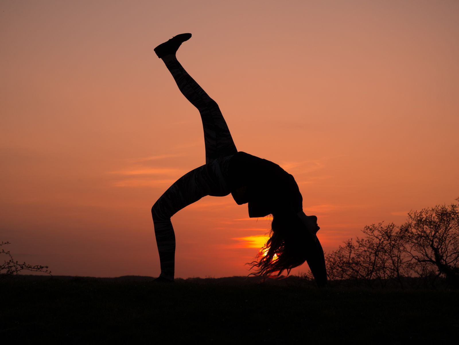 Woman practicing evening yoga outdoors during golden hour sunset