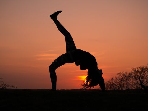 Free Silhouette of a person performing dynamic yoga at sunset, creating a peaceful and vibrant atmosphere. Stock Photo