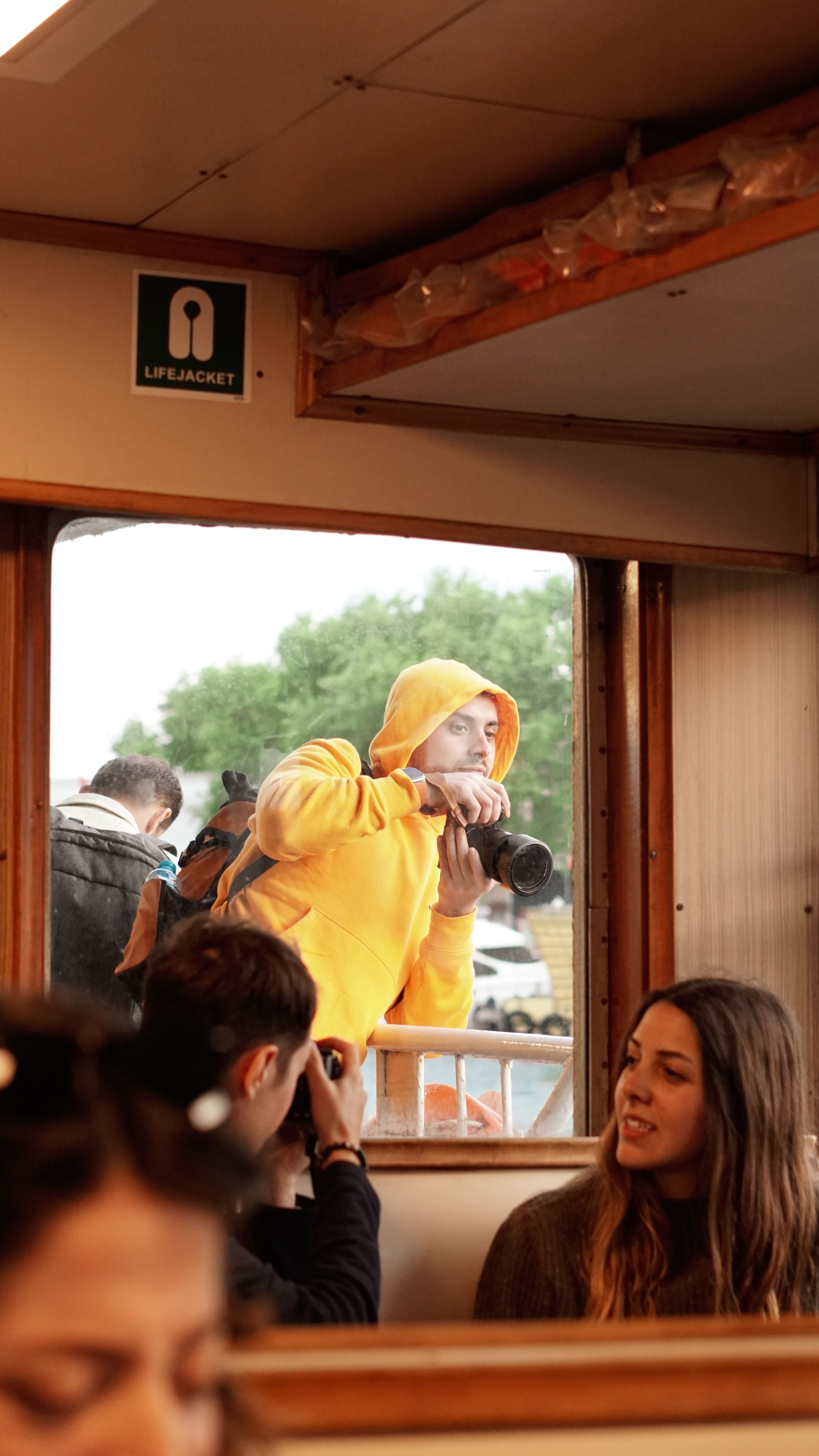 Photographer taking pictures while passengers enjoy a scenic ferry ride.