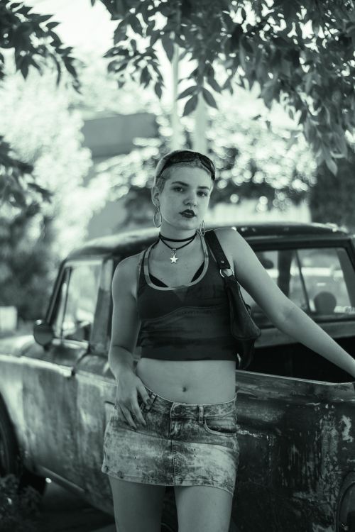 Free A fashionable young woman stands confidently next to a vintage truck on a sunny day. Stock Photo