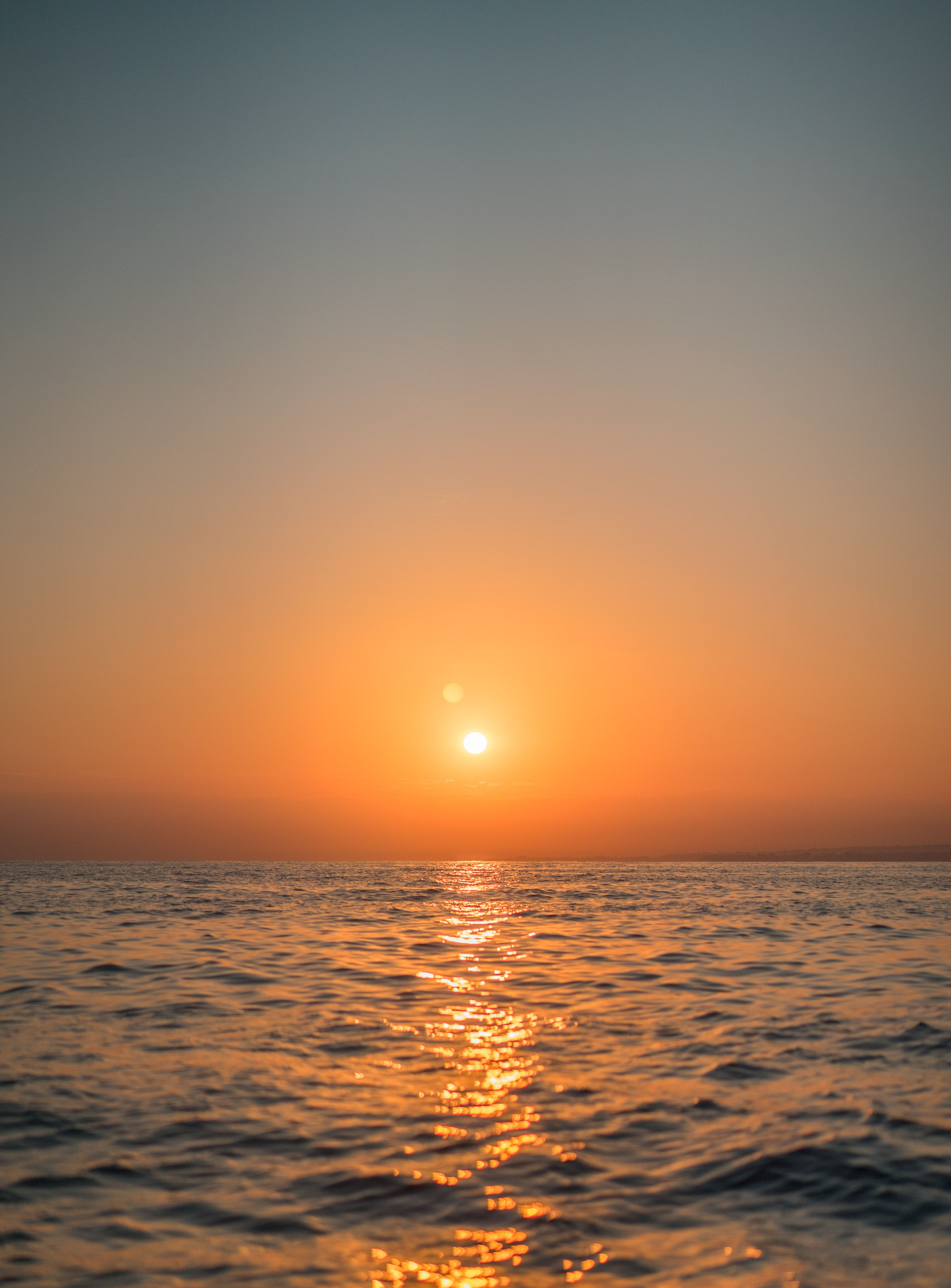 Peaceful ocean sunset showcasing a golden reflection on calm waves, creating a tranquil atmosphere.