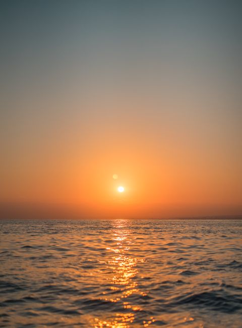 Peaceful ocean sunset showcasing a golden reflection on calm waves, creating a tranquil atmosphere.