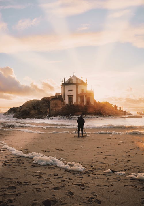 Человек, стоящий на берегу моря с видом на остров во время золотого часа