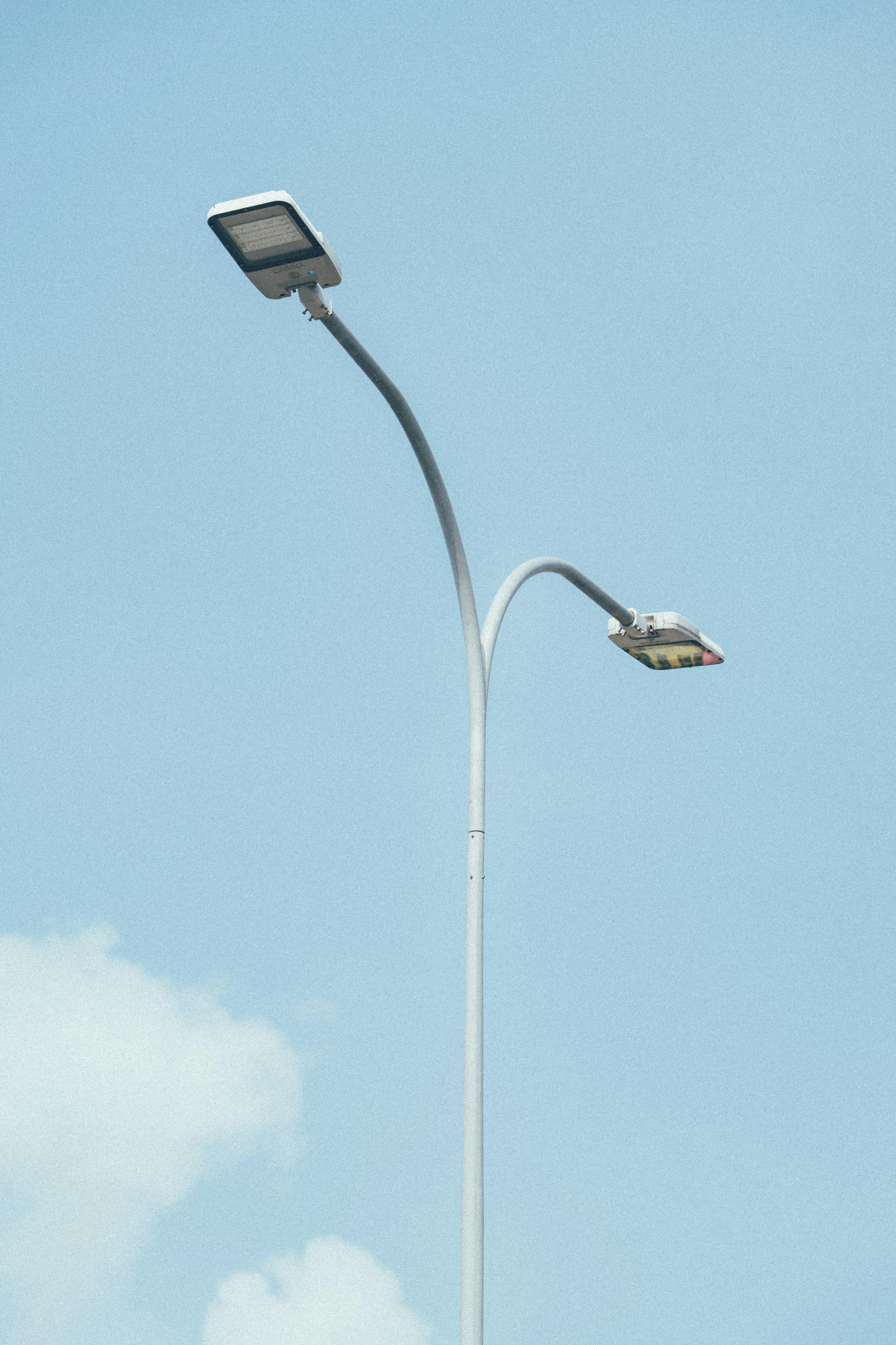 Dual street lamps set against a clear blue sky, showcasing modern urban lighting design.