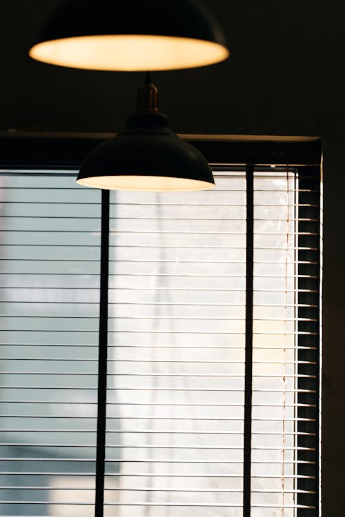 A lamp is hanging over a window with blinds