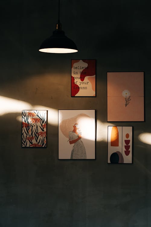 A light fixture hangs above a wall with framed art
