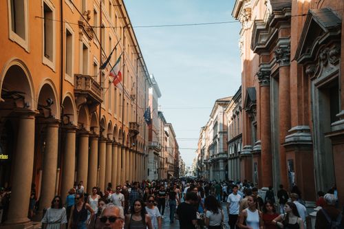 Free A vibrant urban scene in Bologna, Italy, showcasing historic architecture and a lively crowd. Stock Photo