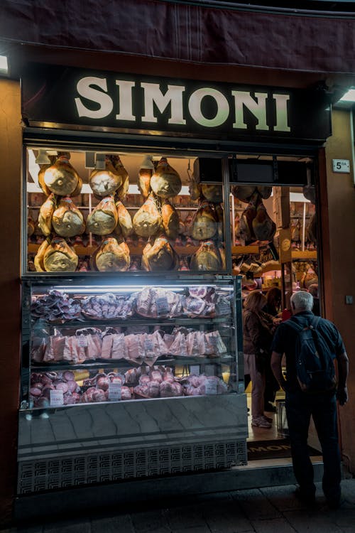 A man standing in front of a shop with meat