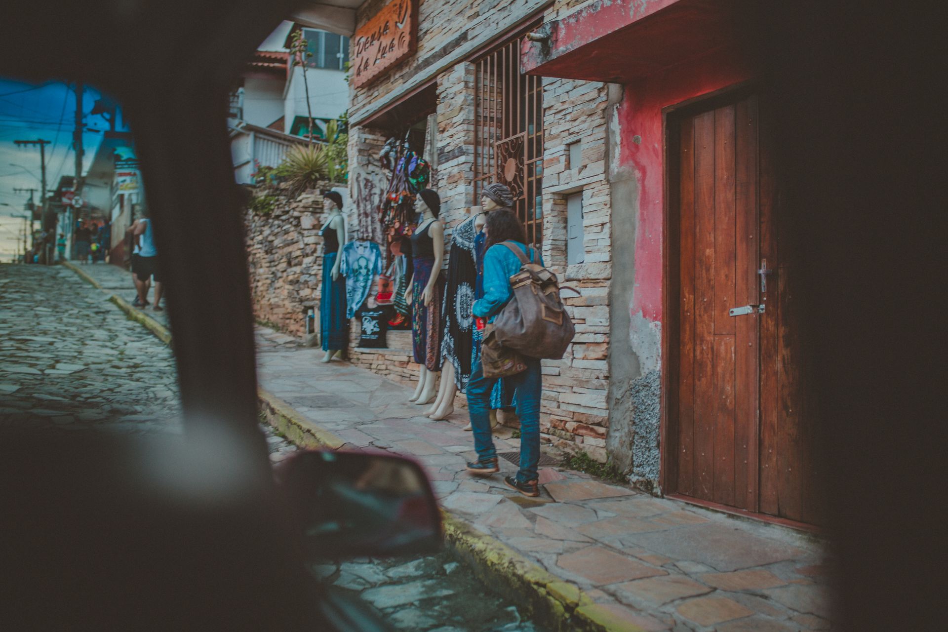 A quaint urban scene with a woman shopping on a cobblestone street by a boutique.