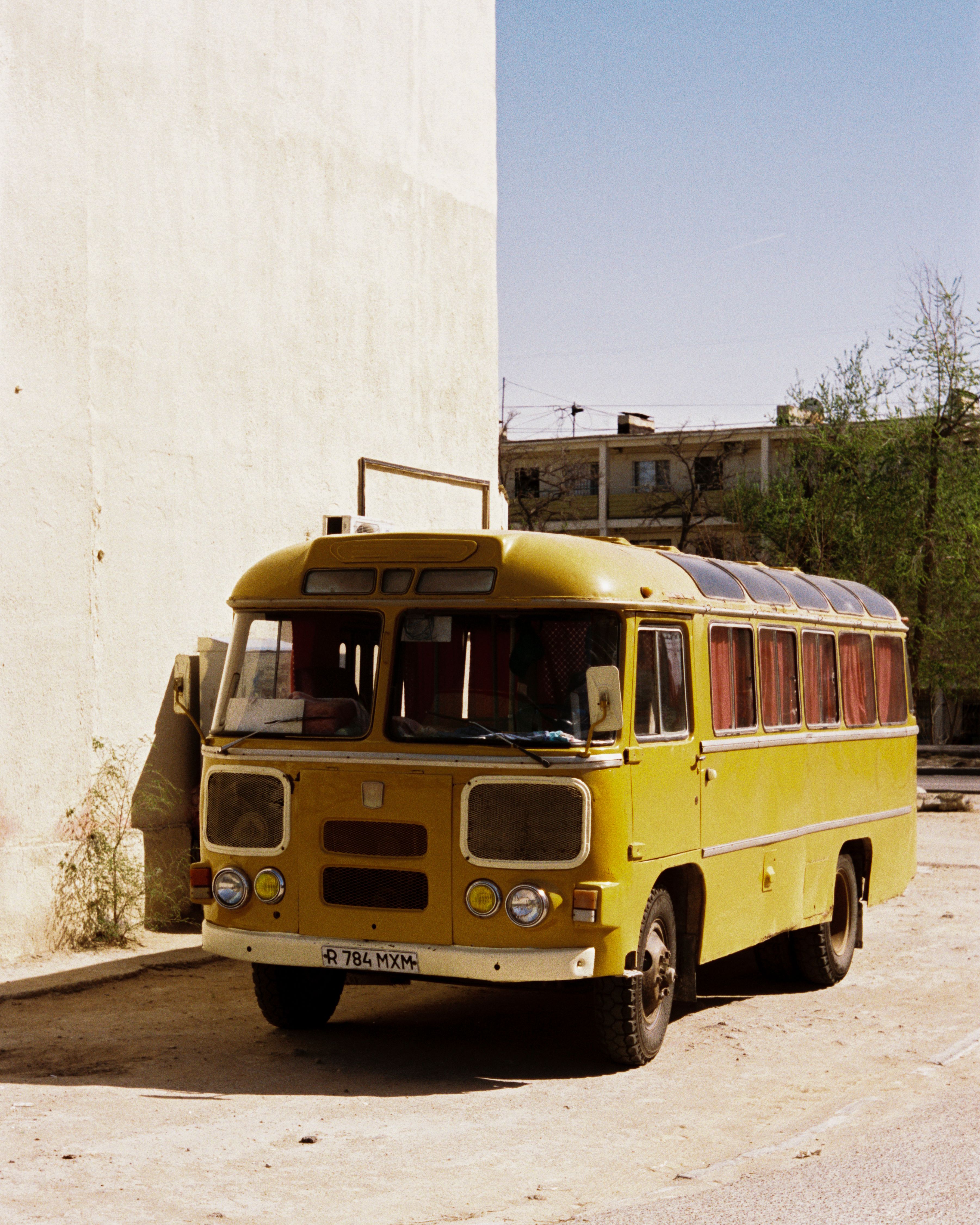 A classic yellow bus parked on a sunny urban street, capturing vintage transportation vibes.