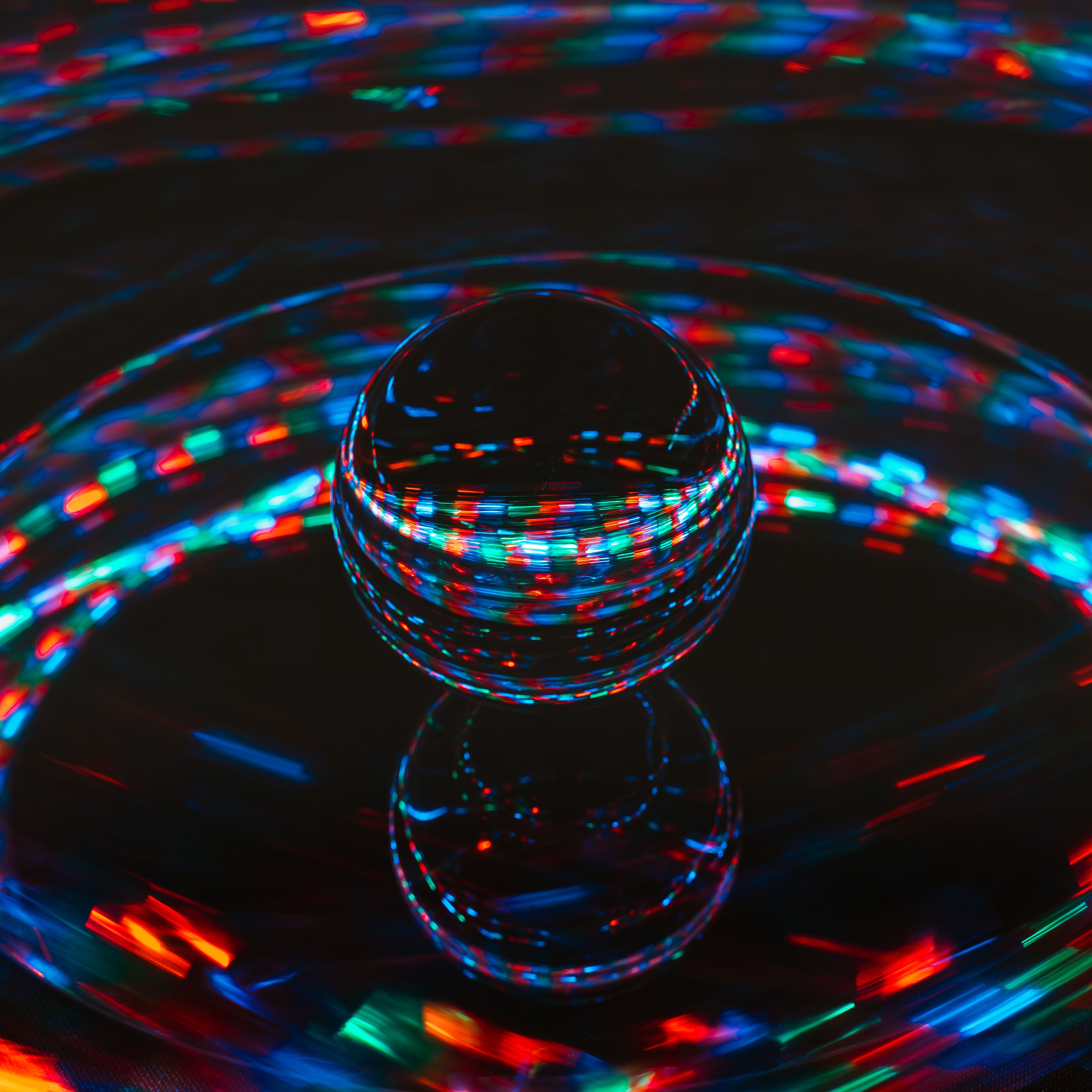 Mesmerizing image of a glass sphere reflecting colorful light trails on a dark surface.