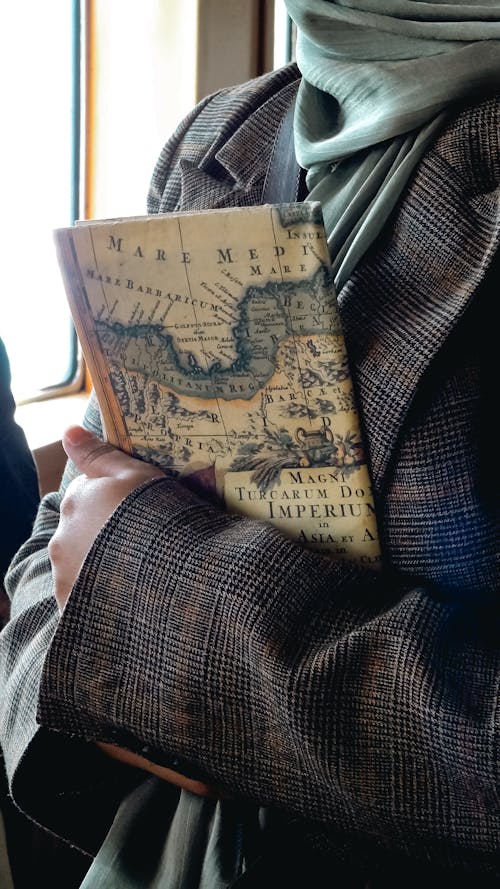 A person holding a book with a map on it