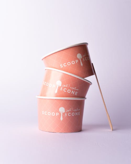 Three ice cream cups with a spoon on top