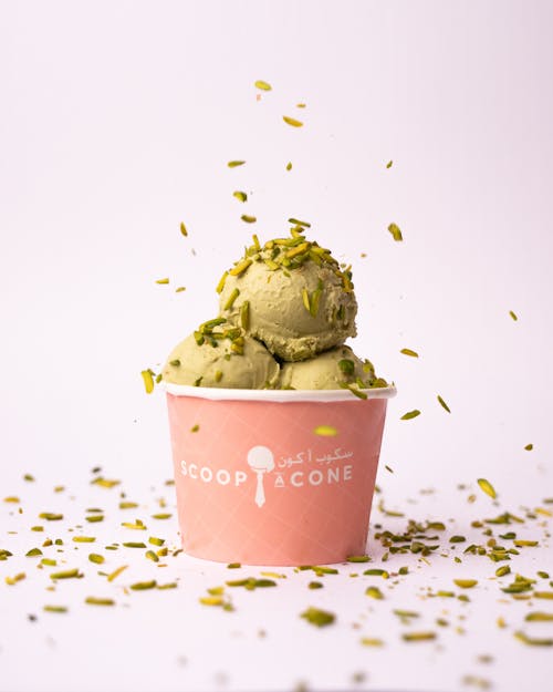 A cup of ice cream with pistachio and sprinkles