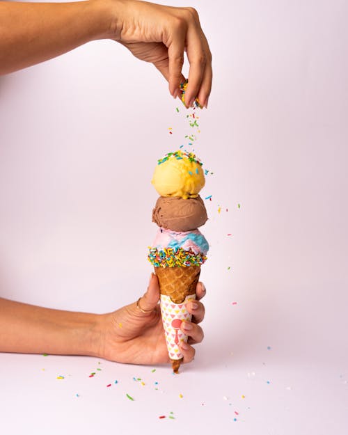 A person holding an ice cream cone with sprinkles