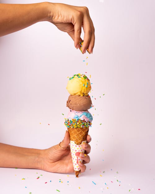 A person is holding an ice cream cone with sprinkles