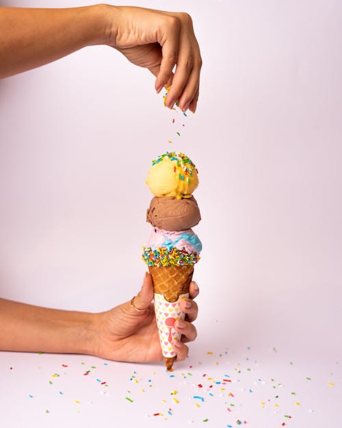 A person holding an ice cream cone with sprinkles