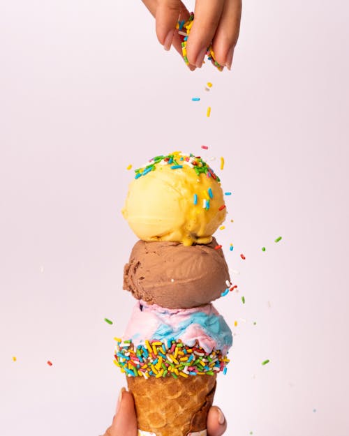 A person is holding up a cone with three different ice cream flavors