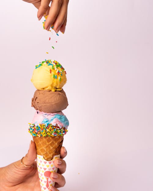 A person is holding an ice cream cone with sprinkles