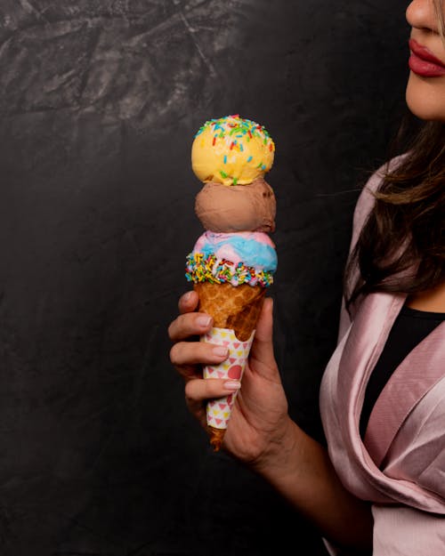 A woman holding an ice cream cone with sprinkles on it