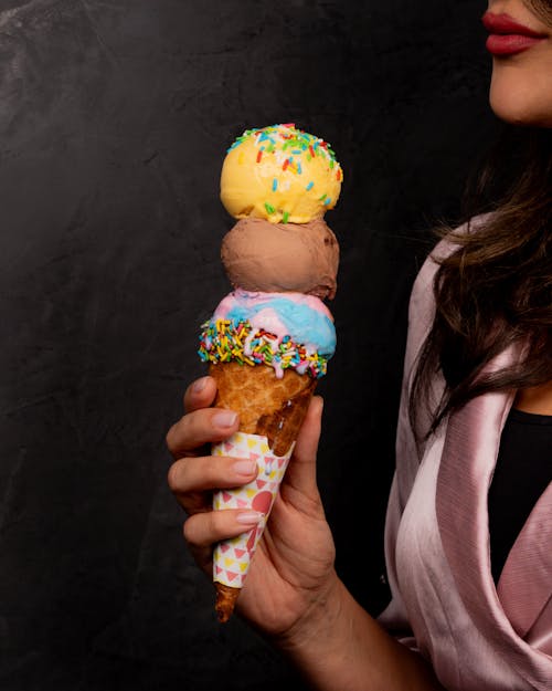 A woman holding an ice cream cone with sprinkles on it
