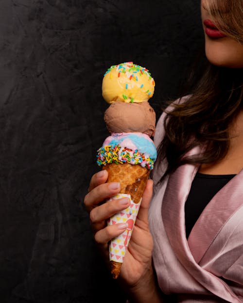 A woman holding an ice cream cone with sprinkles